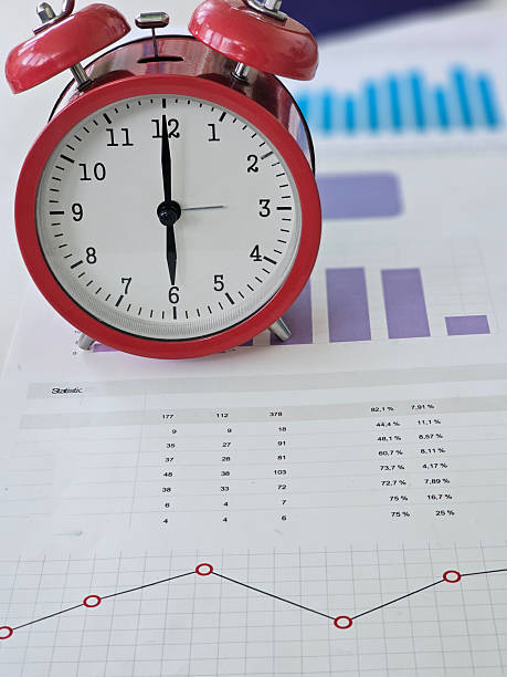 istock Clock on a desk beside financial charts and data representing time management and analysis in a workspace 2215645630