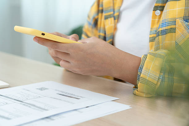 istock woman use phone scan barcode or QR codes to pay credit card bill after receiving document invoice. payment, receive, paying electricity, digital payments, technology, scanning, financial transactions 2215648393