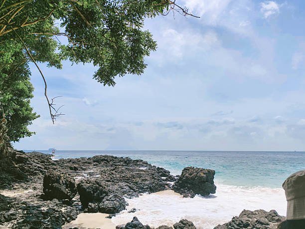 istock Coastline with white sand and scattered black volcanic rocks. A unique tropical beachscape combining natural textures and serene ocean views. Ideal for themes on travel, 2215648561