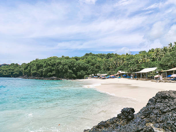 Coastline with white sand and scattered black volcanic rocks. A unique tropical beachscape combining natural textures and serene ocean views. Ideal for themes on travel.