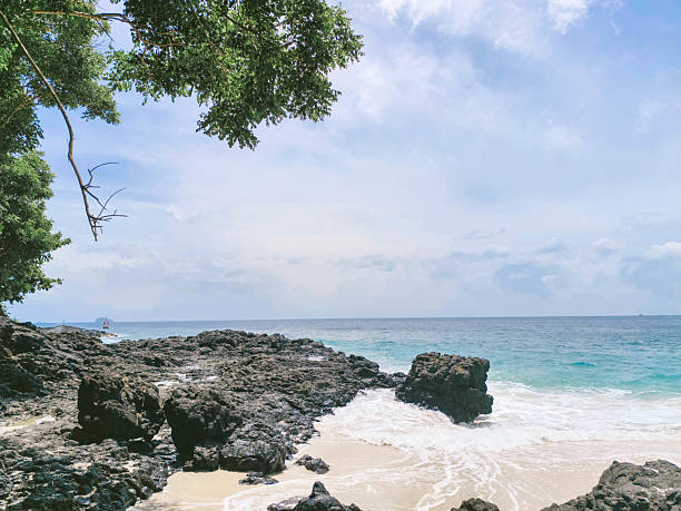 istock Coastline with white sand and scattered black volcanic rocks. A unique tropical beachscape combining natural textures and serene ocean views. Ideal for themes on travel, 2215648571