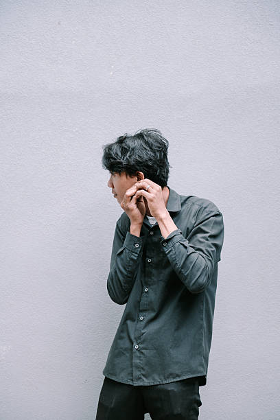 istock Pensive young man adjusting earpiece against a textured wall 2215652278