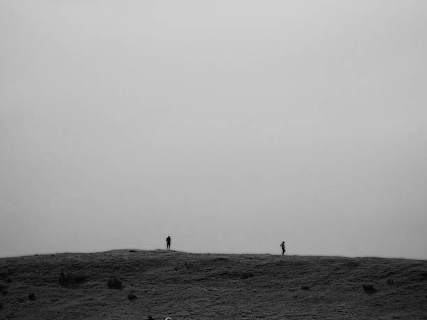 gray scale panorama of two hikers walking along a mountain ridge horizon