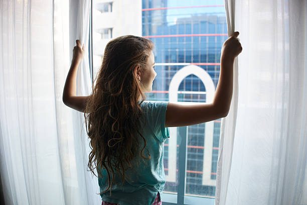 Girl opening curtains to see the view. Travel destinations. Excited.
