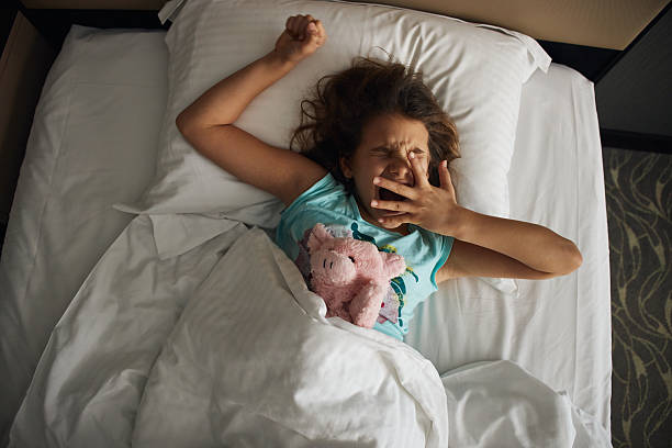 istock Adorable little girl yawning in bed while waking up 2215662904