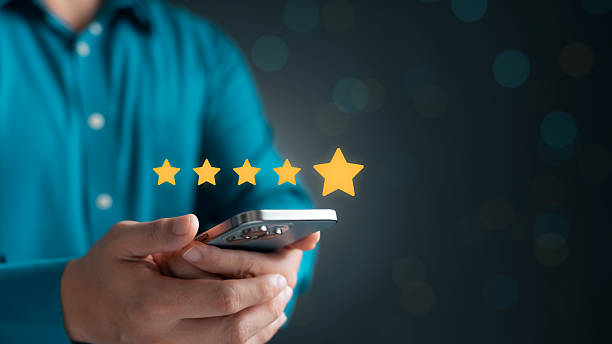 istock Young man holding smartphone displaying five gold stars symbolizing excellence, satisfaction, rating, quality, feedback, digital service, mobile technology, online review, business reputation. 2215663139