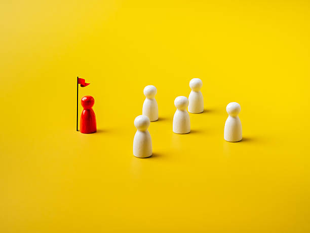 istock The leader red different one stay with flag, leading white peg dolls group, team symbol, isolated on yellow background. Leadership, manager, unique, influencer, talent people, teamwork concept. 2215668942