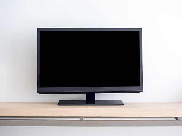 istock Front view of mockup blank space on black smart television with dark empty screen wooden shelf, isolated on white wall background in the hotel bedroom. LED TV with rectangle square space display. 2215668983