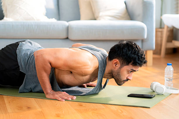istock Young asian man doing pushup exercise in living room at home with determination, man training on yoga mat, bodybuilding strength and fitness for healthy lifestyle, workout routine, self-care. 2215669238