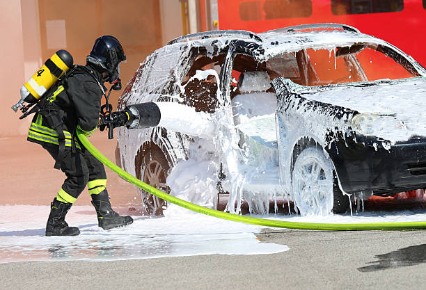 istock Firefighter with helmet and oxygen cylinder while operating   lance with   foam to extinguish   car fire after   road accident 2215670644