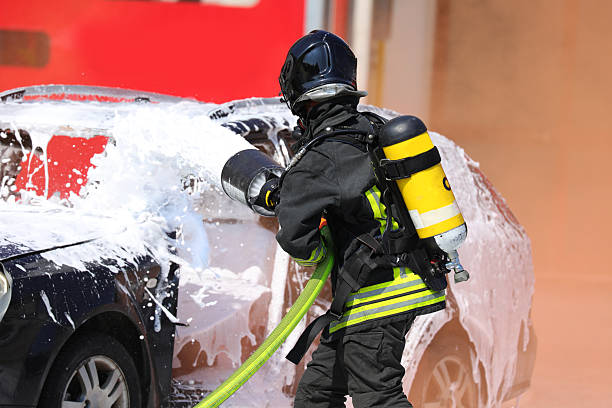 istock Firefighter with   helmet and oxygen tank while spraying   foaming coat to extinguish   fire of   crashed vehicle after   road accident 2215672118