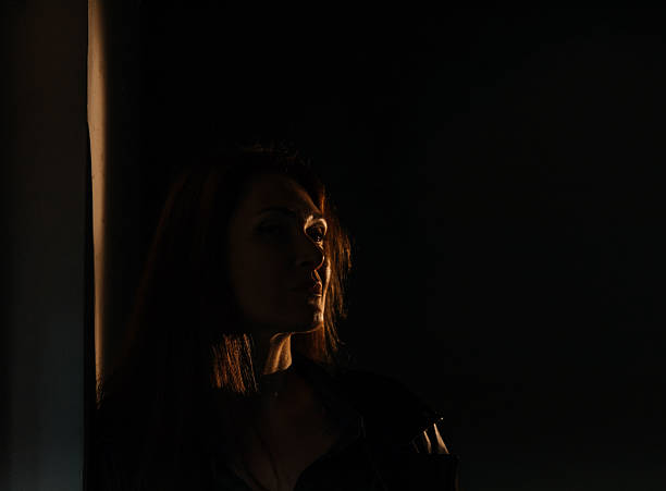 istock Pensive female in dramatic low light with shadow play 2215672251