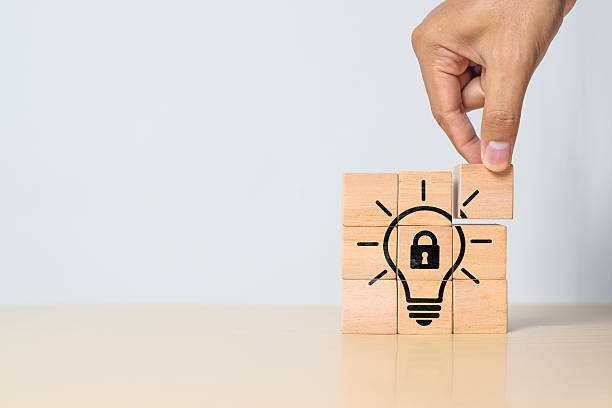 istock Wooden cube with a light bulb and lock symbol representing copyright, patent protection, and intellectual property rights. Suitable for content related to innovation, legal ownership, brand protection, and creative licensing 2215672614