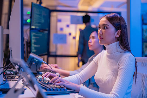 istock young Asian software development manager leads a late-night office discussion with his executive team, mentoring developers and analyzing source code to guide programming and project development 2215674544