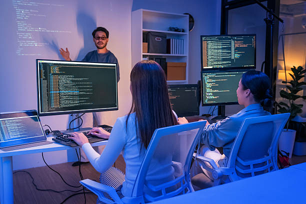 istock young Asian software development manager leads a late-night office discussion with his executive team, mentoring developers and analyzing source code to guide programming and project development 2215674566