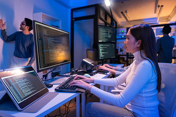 istock young Asian software development manager leads a late-night office discussion with his executive team, mentoring developers and analyzing source code to guide programming and project development 2215674579