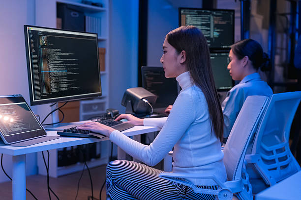 istock young Asian software development manager leads a late-night office discussion with his executive team, mentoring developers and analyzing source code to guide programming and project development 2215674647