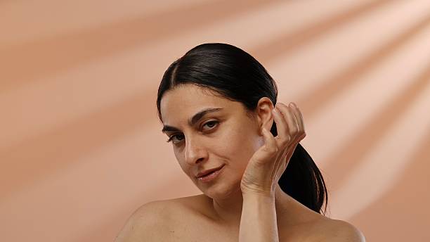 A serene portrait featuring a woman in a natural pose, highlighted by a gentle, beige background that enhances her expression.
