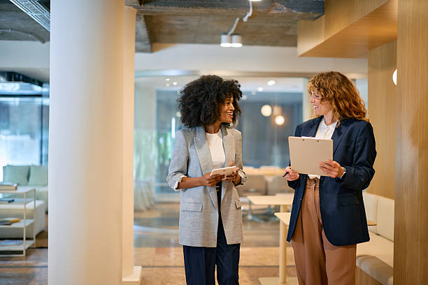 istock Two businesswomen discussing work in modern office using tablet and clipboard 2215687955