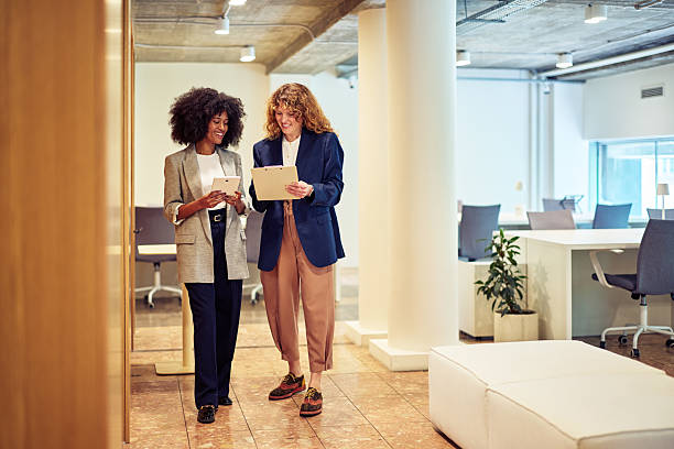 istock Two businesswomen walking and talking in a modern office 2215687971