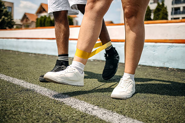 istock People exercising together outdoors using rubber band and assisting each other with focus on legs 2215690905