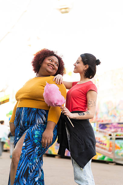 istock Two  women enjoying cotton candy at amusement park 2215691340