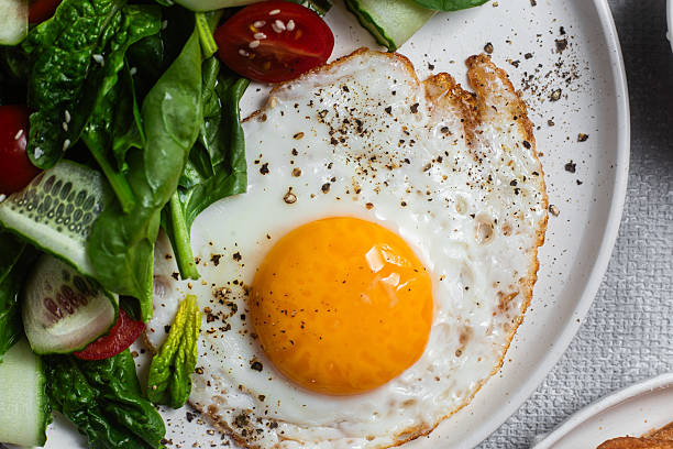 istock Fried egg with spinach, tomato and cucumber salad in a white plate. Healthy breakfast 2215696659
