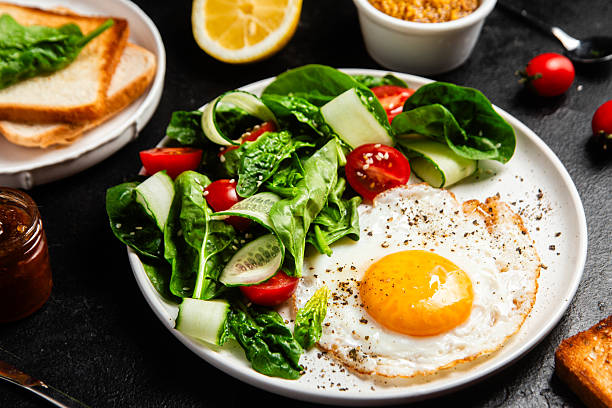 istock Fried egg with spinach, tomato and cucumber salad in a white plate. Healthy breakfast 2215696678