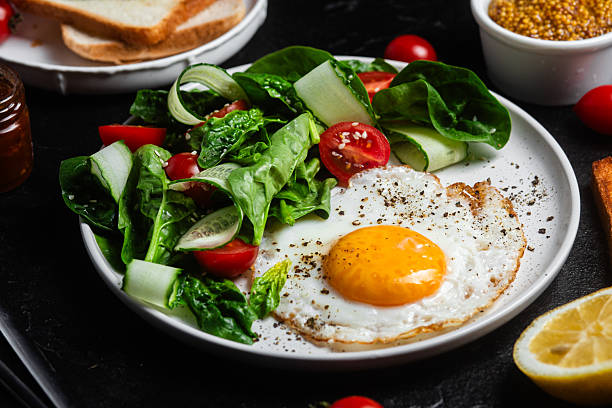istock Fried egg with spinach, tomato and cucumber salad in a white plate. Healthy breakfast 2215696706