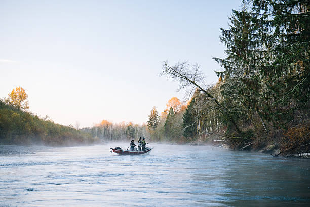 Young couple drifting down river in rowboat fishing for salmon and steelhead trout, autumn, distant view. Guided drift fishing trip, Washington State