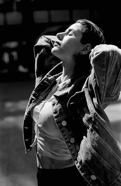 istock Young woman enjoying sunlight with denim jacket and hands behind head 2215712013