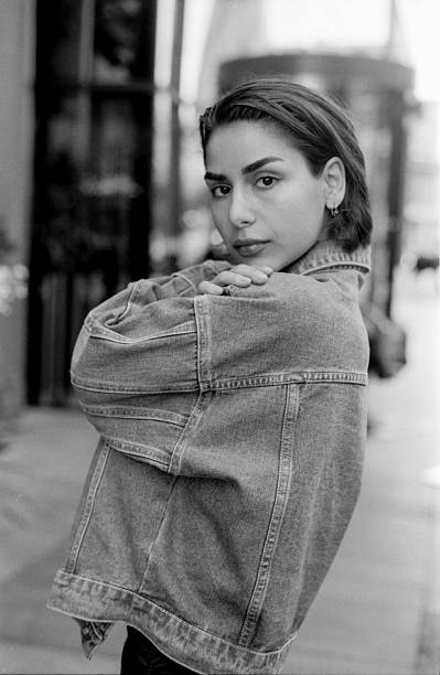 istock Young woman wearing denim jacket posing in urban setting, grainy analog style 2215712017