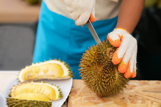 istock Worker Cutting Durian Fruit at Market Stall 2215717432