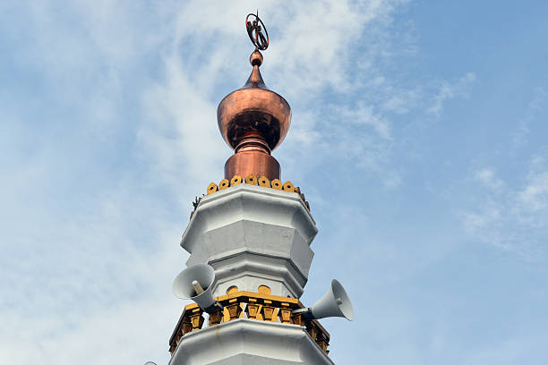 Beautiful white and gold mosque minaret against blue sky and white clouds