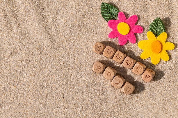 istock Summer 2025 message in sand with colorful felt flowers 2215724535