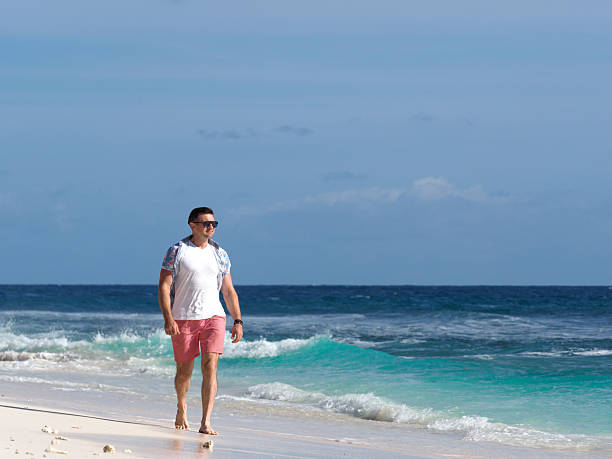 istock Attractive man walking on stunning white sand beach 2215725807