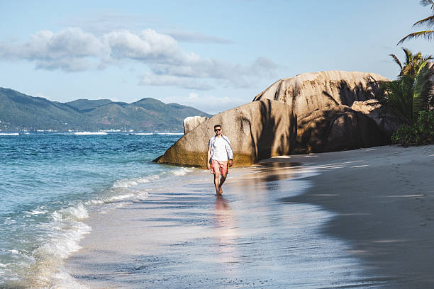 istock Attractive man walking on stunning white sand beach 2215726073
