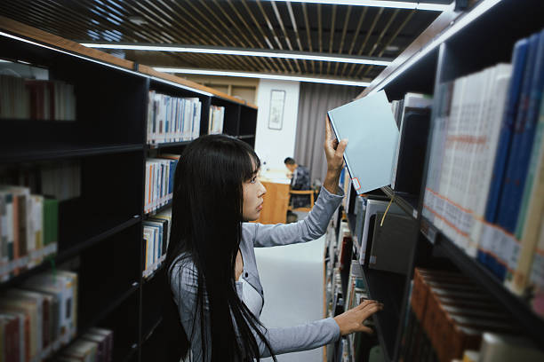 Group of multiethnic students picking books from bookshelf in a library