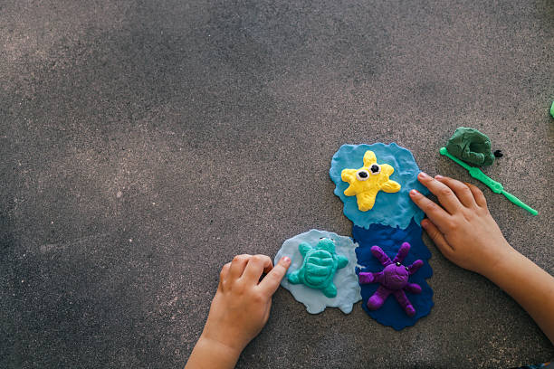 istock Children's hands sculpting sea animals like starfish, turtle, and octopus using bright modeling clay on a dark surface, surrounded by tools and unused clay packs 2215729813