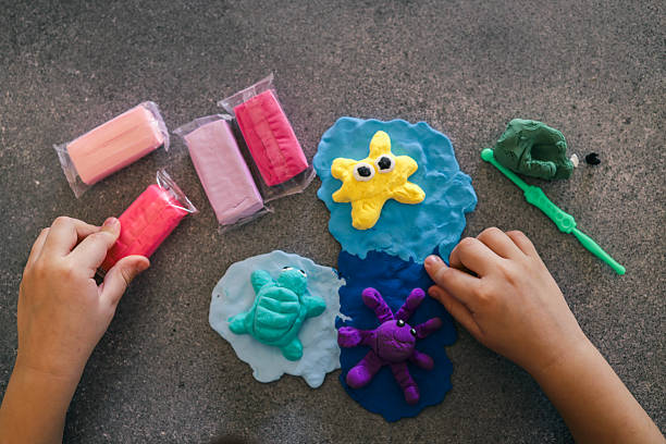 istock Children's hands sculpting sea animals like starfish, turtle, and octopus using bright modeling clay on a dark surface, surrounded by tools and unused clay packs 2215729819