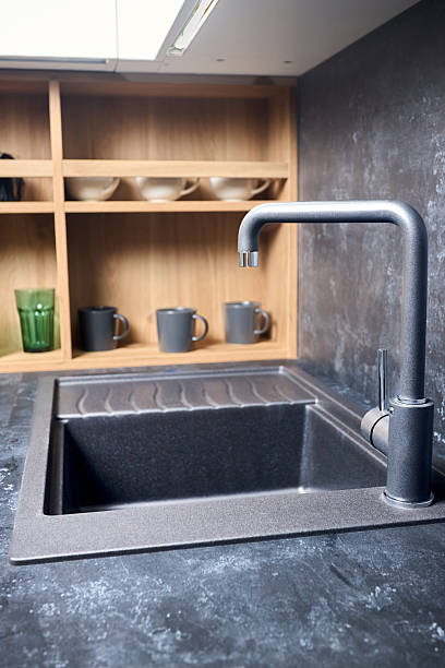 istock Interior of contemporary green and red kitchen. Luxury modern fitted flat design kitchen with square stoneware sink and tap wooden shelves cupboard sideboard with dish drying cabinet vertical shot. 2215737340