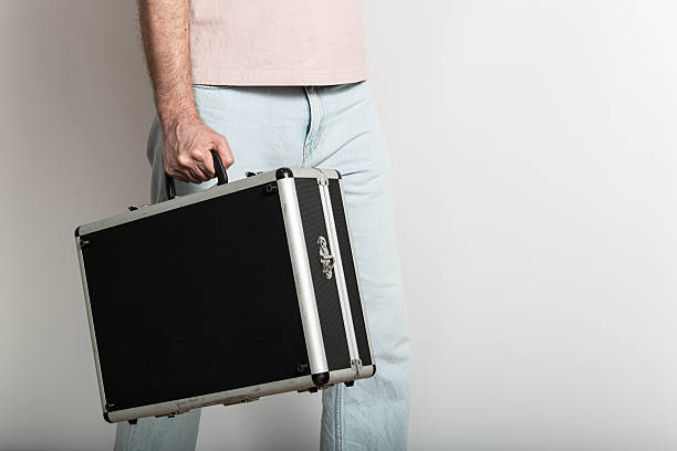 istock A person stands in a simple indoor environment, holding a black briefcase. The setting features neutral colors, suggesting a casual yet professional atmosphere 2215740099