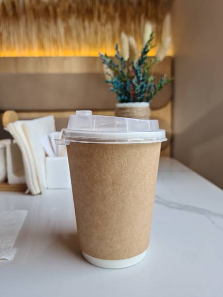 istock Disposable Coffee Cup with Lid in Minimalist Style: Beige Backdrop and White Tabletop