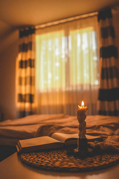 istock Extinguished twisted candle releasing smoke beside an open book on a cozy bed, with warm ambient lighting in a peaceful bedroom 2215755049
