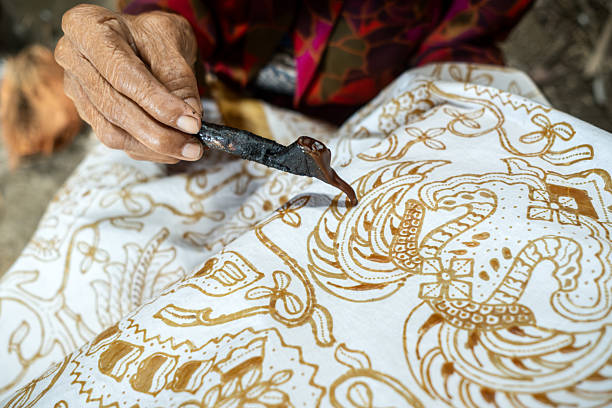 istock Indonesian artisan drawing traditional batik pattern on fabric 2215756757