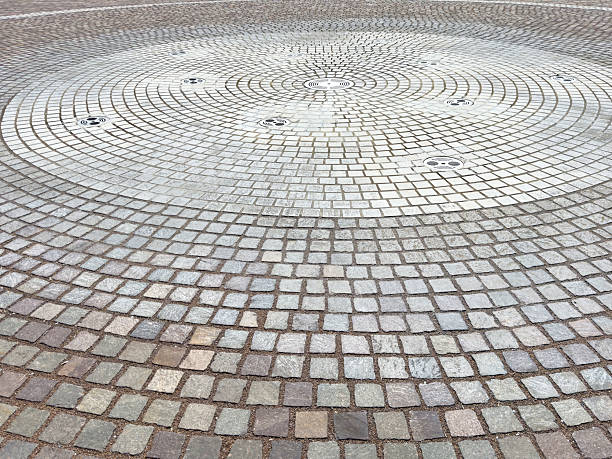 Circular stone pavement with intricate pattern and water fountains, lifestyle
