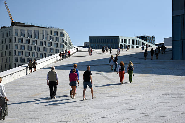 The Oslo Opera House is a beautiful large building completed in 2008, located next to the sea. The Building was realized after plans by Snøhetta architects. The angled exterior surfaces of the building are covered with marble from Carrara. Captured with some tourists walking to the rooftop during summer season.