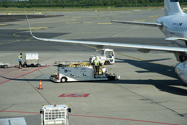 Oslo Airport Gardermoen is an international airport serving Oslo, the capital and most populous city of Norway. The image shows a maintenance vehicle next an aircraft, captured during summer season.