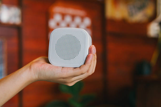 istock Hand Holding a Small Portable Speaker in a Cozy Decor Environment with a Warm Background 2215780103