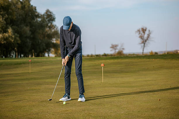 istock Man playing golf on a sunny day putting on green 2215782613